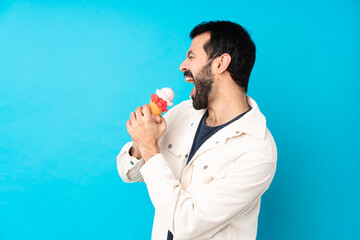 Young man with a cornet ice cream over isolated blue background