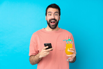 Young man over holding a cocktail over isolated blue background surprised and sending a message