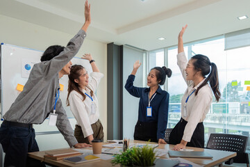 Business team celebrate corporate victory together in office, laughing and rejoicing, smiling excited employees colleague screaming with joy in office