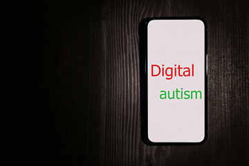 Smartphone with phrase Digital Autism on wooden table, top view and space for text. Addictive...