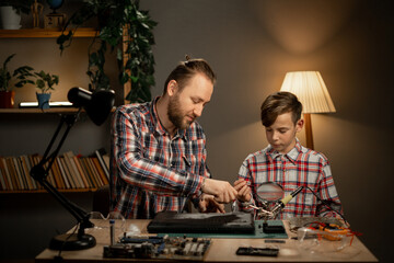 A father teaches his son how to repair a broken laptop and a damaged hard drive, a hobby for...