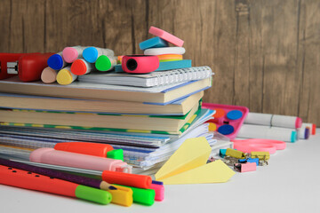 Many different books, paper plane and school stationery on white table, closeup. Back to school