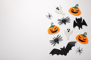 Flat lay composition with bats, pumpkins, ghosts and spiders on white background, space for text....