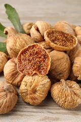 Tasty dried figs and green leaf on light wooden table, closeup