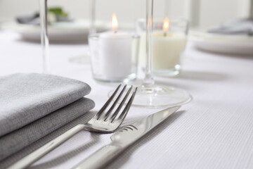 Beautiful table setting with silverware and candles, closeup