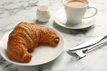 Delicious fresh croissant served with coffee on light marble table