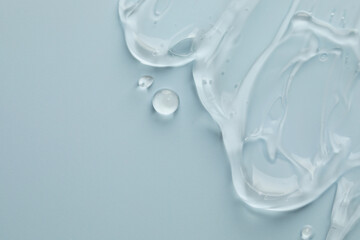 Clear cosmetic gel on light blue background, top view. Space for text