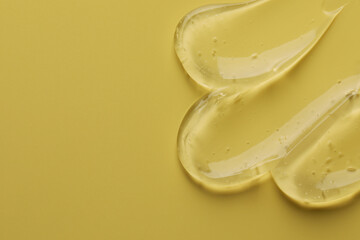 Sample of clear cosmetic gel on yellow background, top view. Space for text