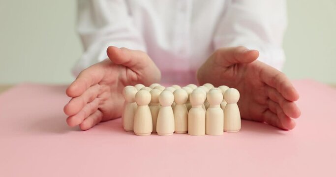 Female hands close wooden dolls on the table, close-up. The concept of community protection,