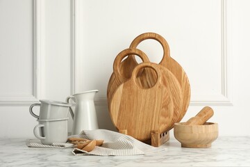 Wooden cutting boards, spoons and dishware on white marble table