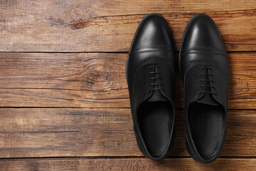 Pair of black leather men shoes on wooden background, top view. Space for text