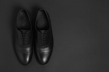 Pair of leather men shoes on black background, top view. Space for text