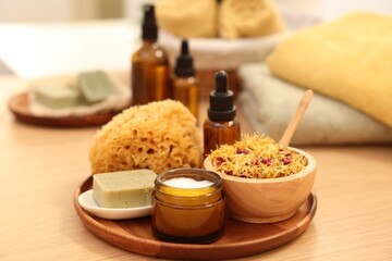 Dry flowers, loofah, soap bar, bottle of essential oil and jar with cream on wooden table. Spa time