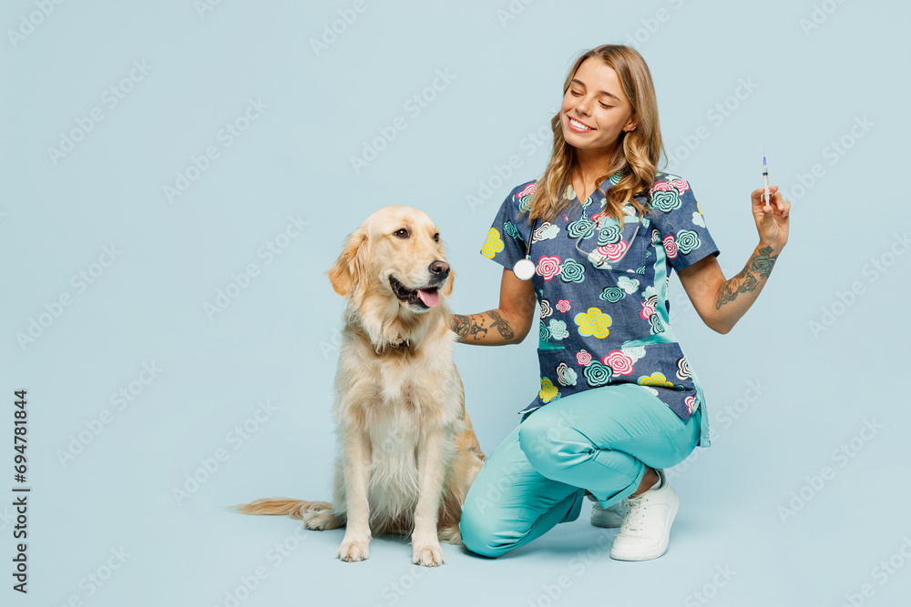 Wall mural Full body young veterinarian woman wearing uniform stethoscope heal exam hug embrace retriever dog do vaccine injection isolated on plain pastel light blue background studio. Pet health care concept.