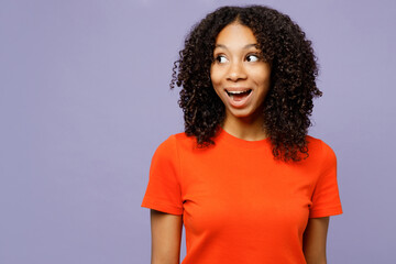 Little surprised shocked kid teen girl of African American ethnicity wear orange t-shirt look aside...