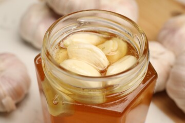 Honey with garlic in glass jar on table, closeup