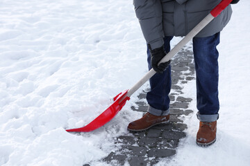 Man removing snow with shovel outdoors, closeup - obrazy, fototapety, plakaty