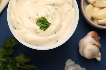 Tasty sauce with garlic and parsley on blue table, top view