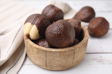 Fresh salak fruits in bowl on white wooden table, closeup