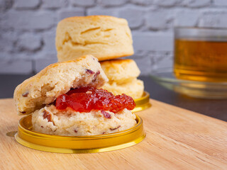 Scones traditional are delicious with strawberry jam on a wooden tray.