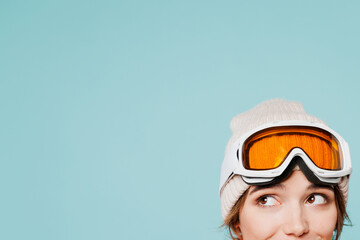 Close up cropped shot photo of skier young woman wearing heat ski goggles mask look aside on area mockup travel rest spend weekend winter season in mountains isolated on plain pastel blue background. - obrazy, fototapety, plakaty