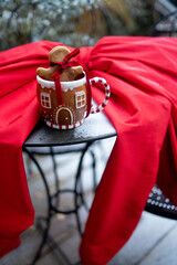 Festive cup with gingerbread cookie on table with red bow outdoors. Homemade gingerbreads and...