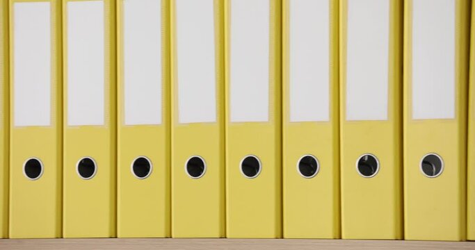 Yellow folders stand in a row, close-up. Stationery, office supplies, slowmotion