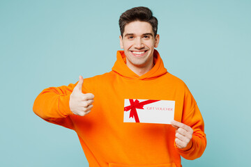 Young man he wearing orange hoody casual clothes hold gift certificate coupon voucher card for...