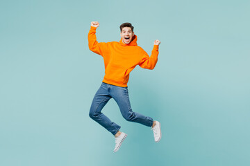 Full body overjoyed young man he wears orange hoody casual clothes jump high do winner gesture...