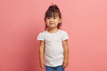 Handsome three years old little asian girl wearing in white shirt standing on a pink isolated. 