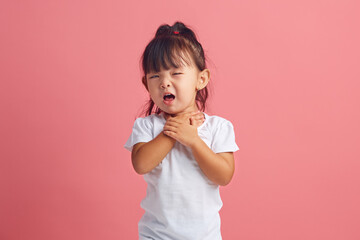 Frustrated little girl keeping throat and coughs having painful feelings or asthma attack. 