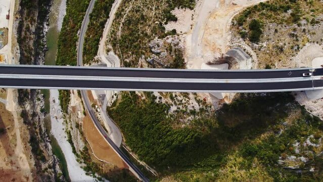 Top drone view of new modern expensive highway asphalt two lane road bridge over the Moraca river canyon in Montenegro, Europe. Motorway of reinforced concrete bridge in picturesque mountain valley.