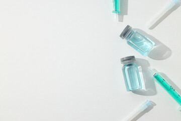 Glass medical bottles with vaccine and syringes on white background, space for text
