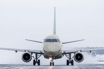 Front view of the passenger jetliner taxiing on taxiway in snowy winter day
