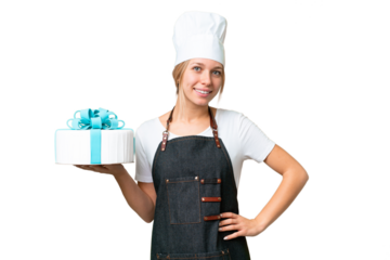 Young pastry blonde woman with a big cake over isolated chroma key background posing with arms at hip and smiling