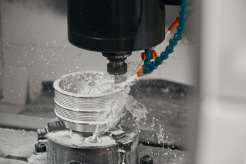 CNC milling machine cutting aluminium automotive part with a coolant liquid. Hi-Technology...