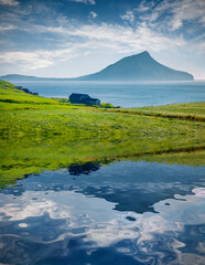 Small pond in Sydradalur village with Koltur on background. Calm morning scene of Streymoy island, Faroe, Denmark, Europe. Beauty of nature concept background..