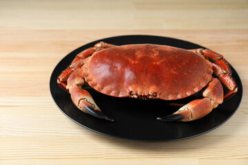 Plate with delicious boiled crab on wooden table