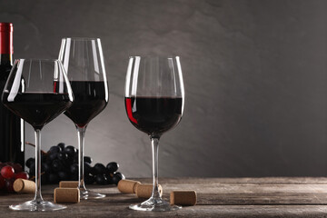 Winemaking. Tasty wine, ripe grapes and corks on wooden table against gray background, space for...