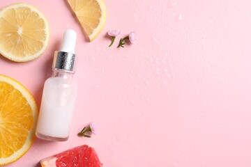 Bottle of cosmetic serum, sliced citrus fruits and small flowers on wet pink background, flat lay. Space for text