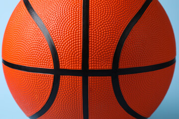 Obraz premium One orange basketball ball on light blue background, closeup