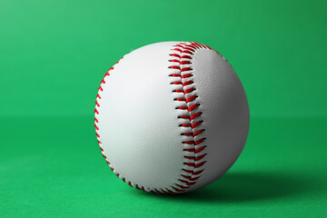 One baseball ball with stitches on green background