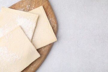Raw puff pastry dough on white table, top view. Space for text