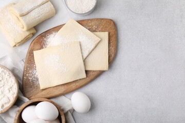 Raw puff pastry dough and ingredients on white table, flat lay. Space for text