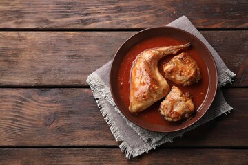 Tasty cooked rabbit meat with sauce on wooden table, top view. Space for text