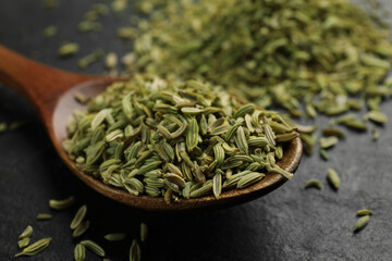 Spoon with fennel seeds on gray table, closeup