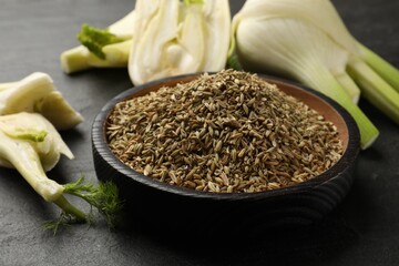 Fresh fennel bulbs and seeds in bowl on gray table, closeup