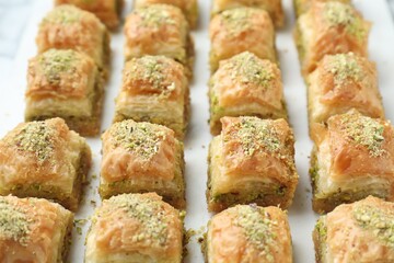 Delicious fresh baklava with chopped nuts on white table, closeup. Eastern sweets