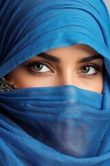 Naklejka premium Close-up portrait of a beautiful Arab Muslim woman wearing a blue hijab. Only the eyes and direct gaze into the camera are visible.