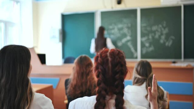 Girl students raise their hands in math class.